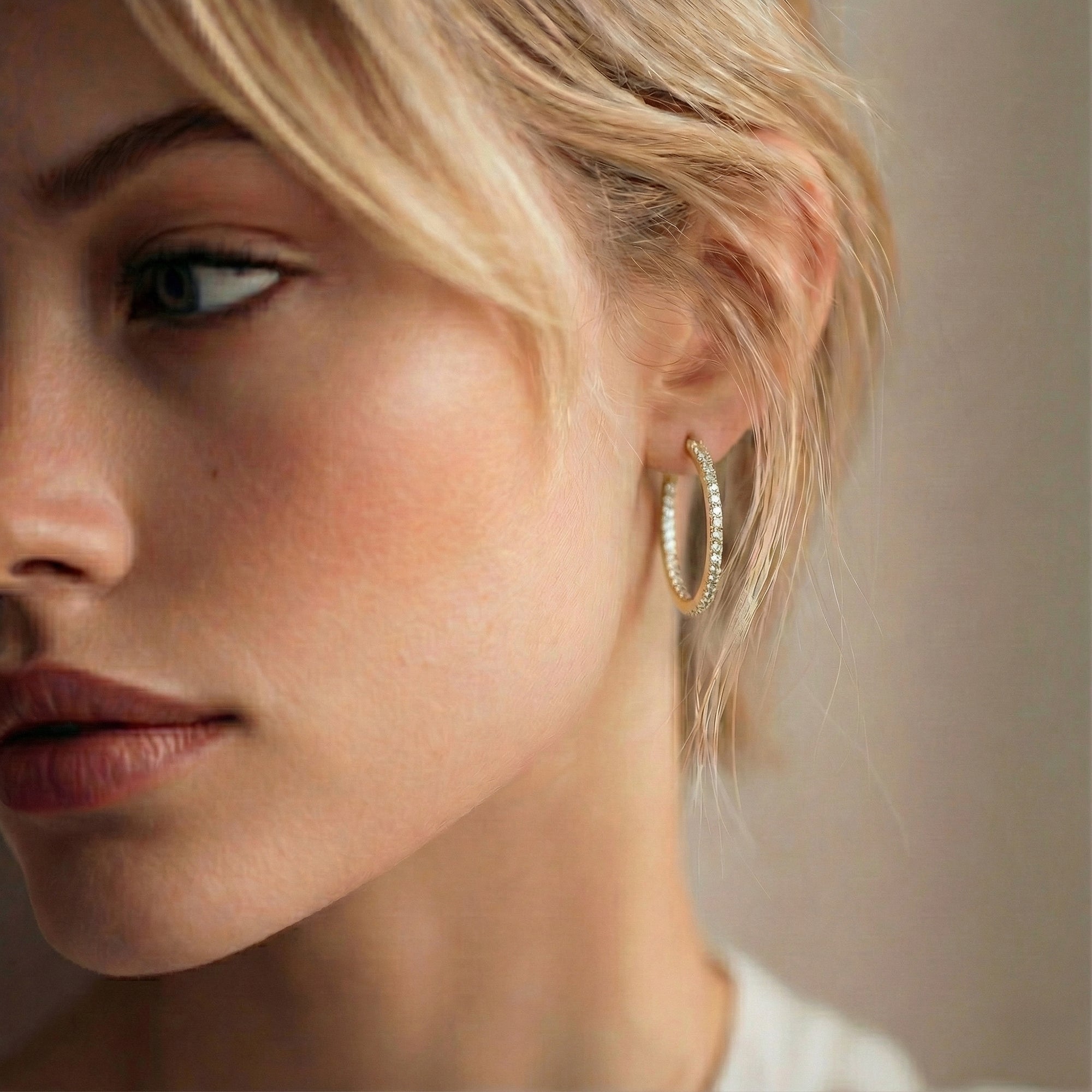 תקריב של פנים של אישה שעונדת עגילי חישוק זהב משובצים