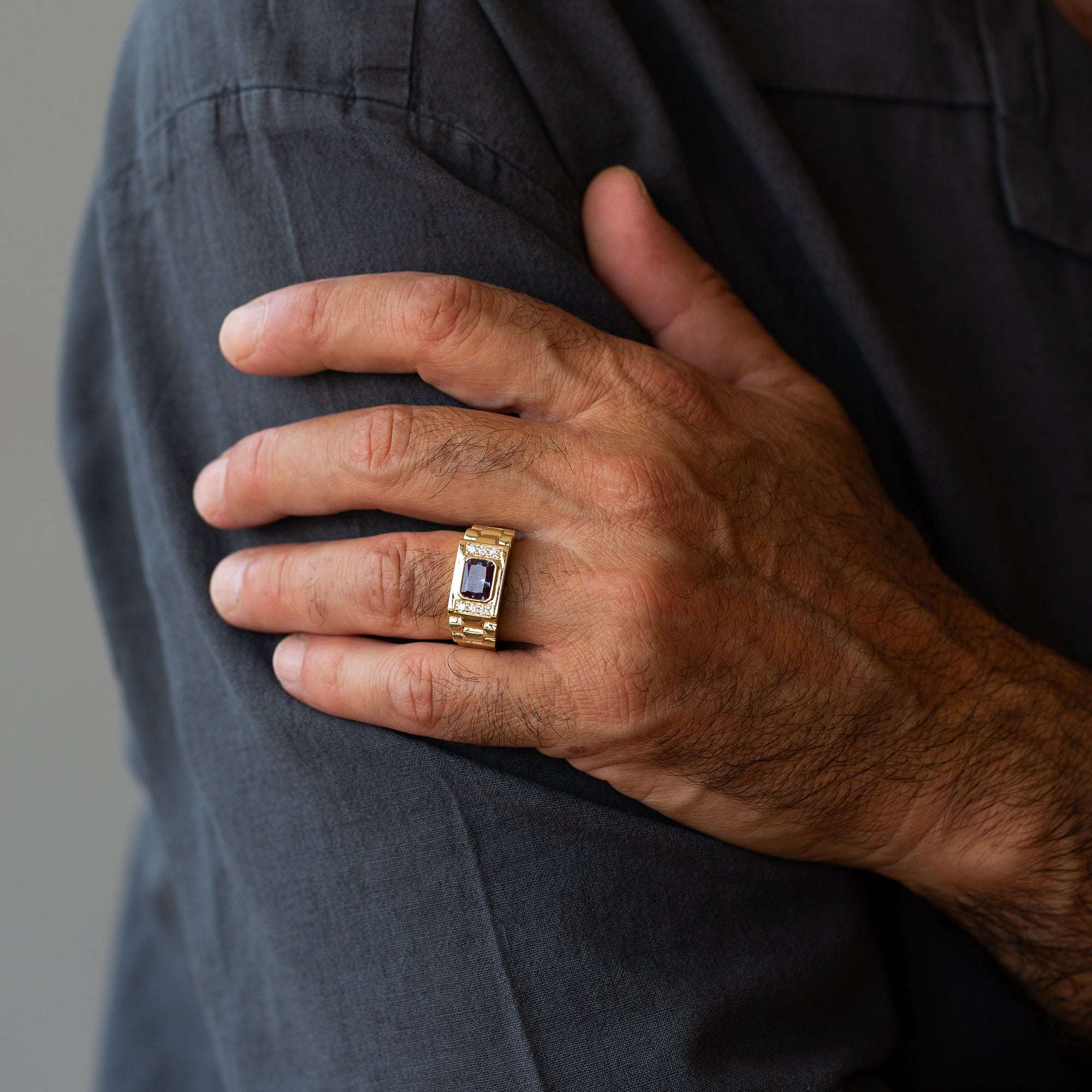 יד של גבר שעונד טבעת לגבר זהב עם אלכסנדריט ויהלומים, מראה מלא של חלקה העליון