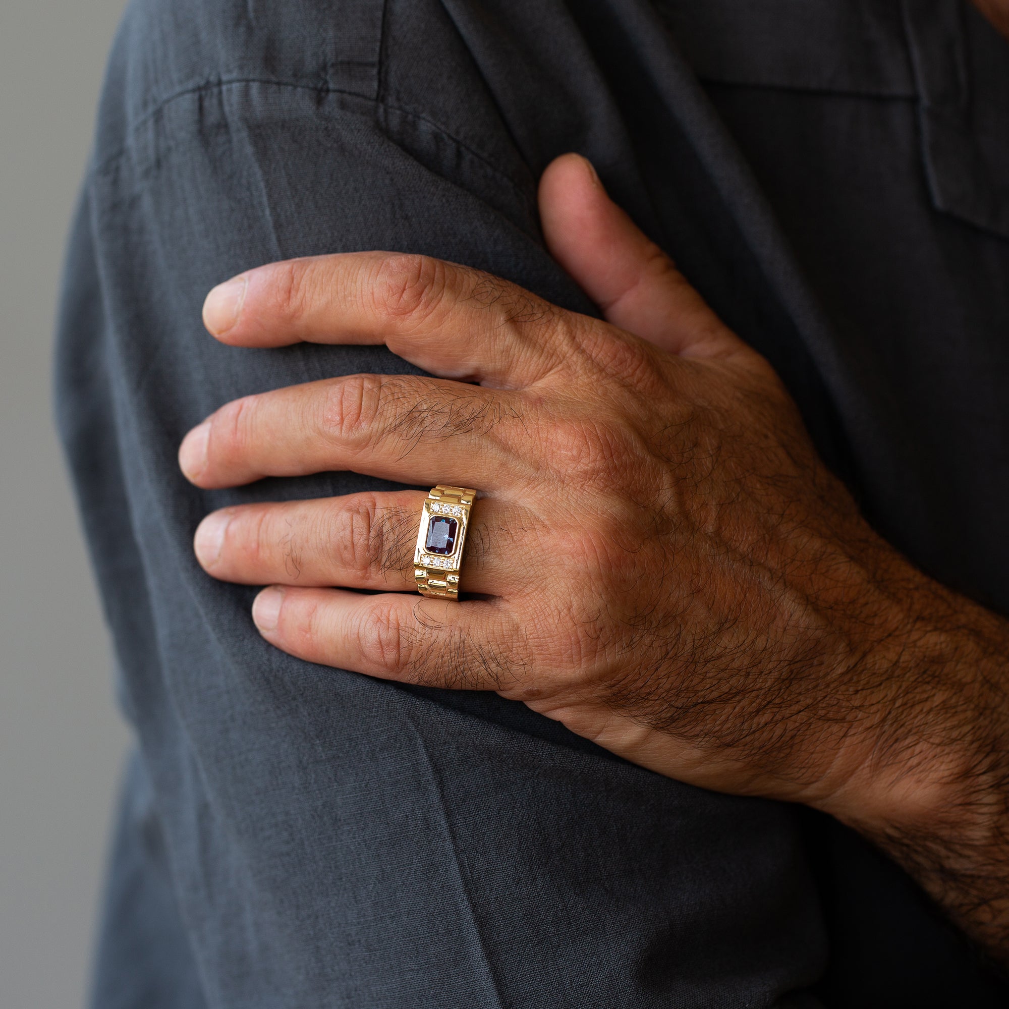 יד של גבר שעונד טבעת לגבר זהב עם אלכסנדריט ויהלומים, מראה מלא של חלקה העליון