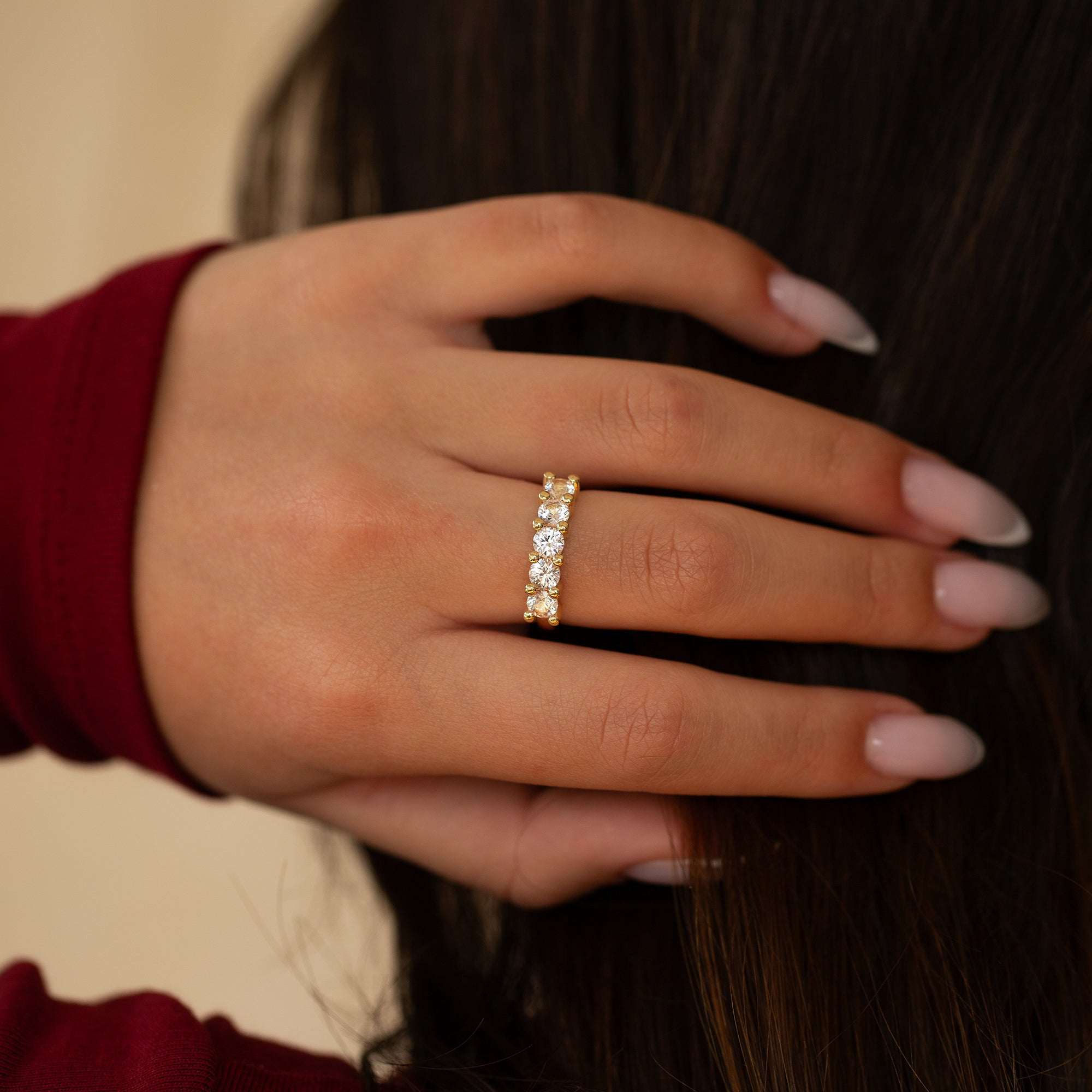 יד של אישה עונדת טבעת זהב 14 קראט משובצת אבני חן ורודות