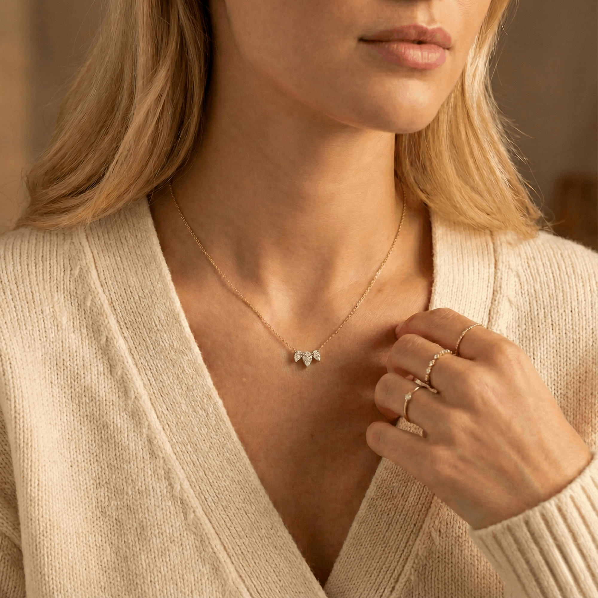 תקריב של אישה שעונדת שרשרת יהלומים משובצת שלושה יהלומים טיפה