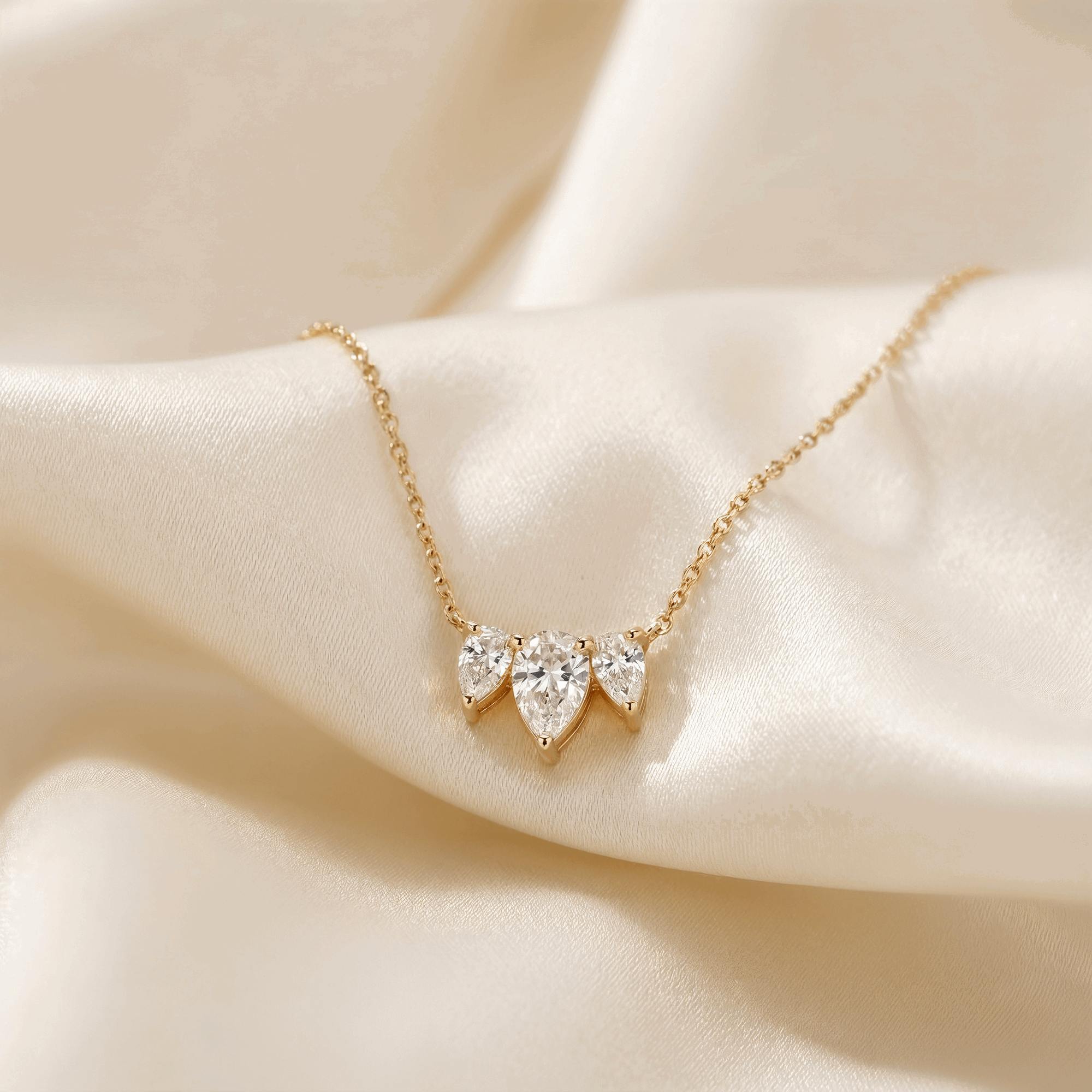 תקריב של שרשרת יהלום טיפה בזהב צהוב על רקע בד בהיר