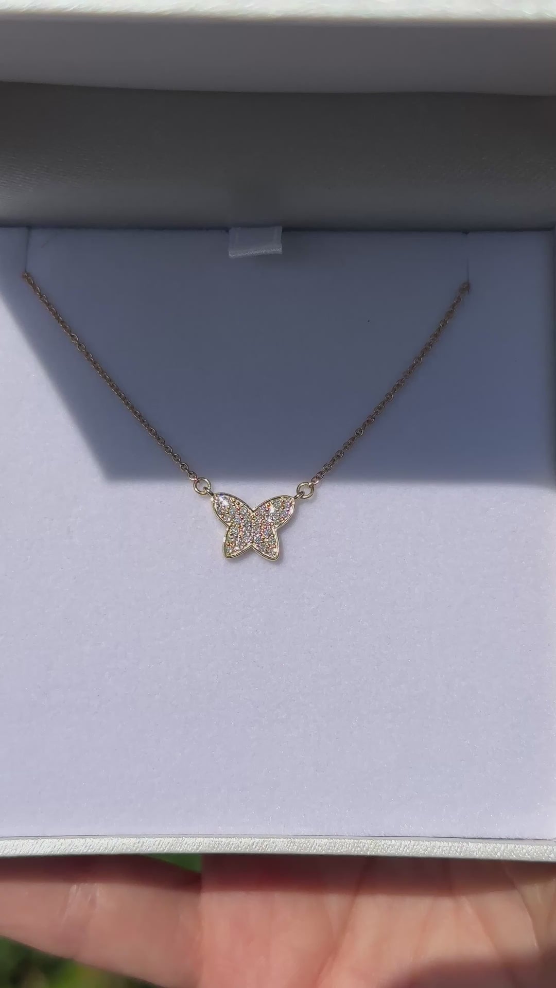 תקריב של תליון פרפר משובץ יהלומים בתוך קופסת תכשיטים