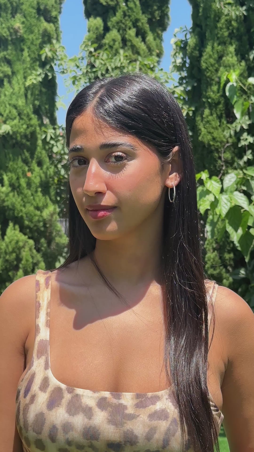 אישה עם חולצה מנומרת עונדת ומראה עגילי חישוק יהלומים מזהב 