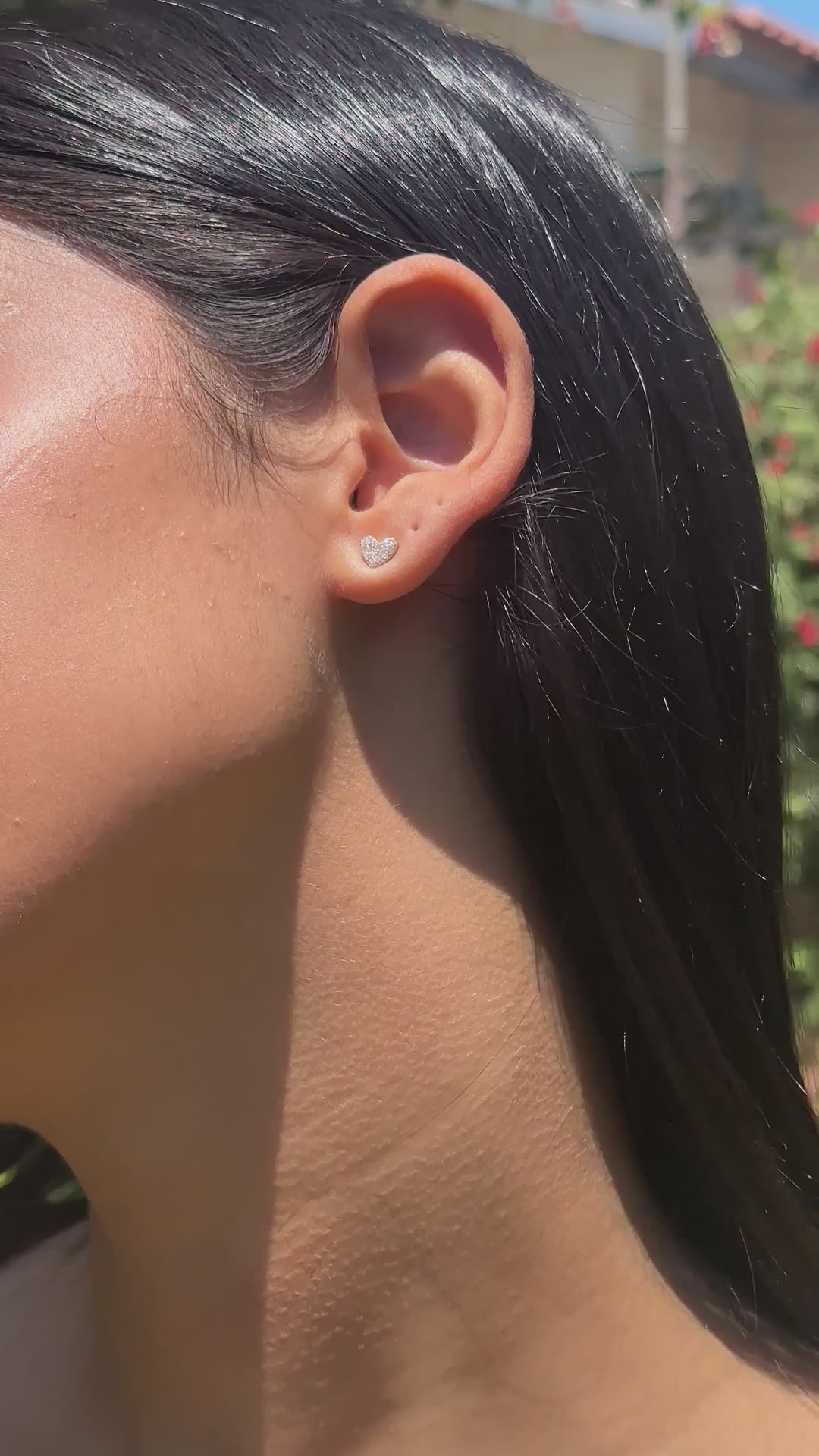 אישה צעירה עונדת עגילי לבבות מזהב