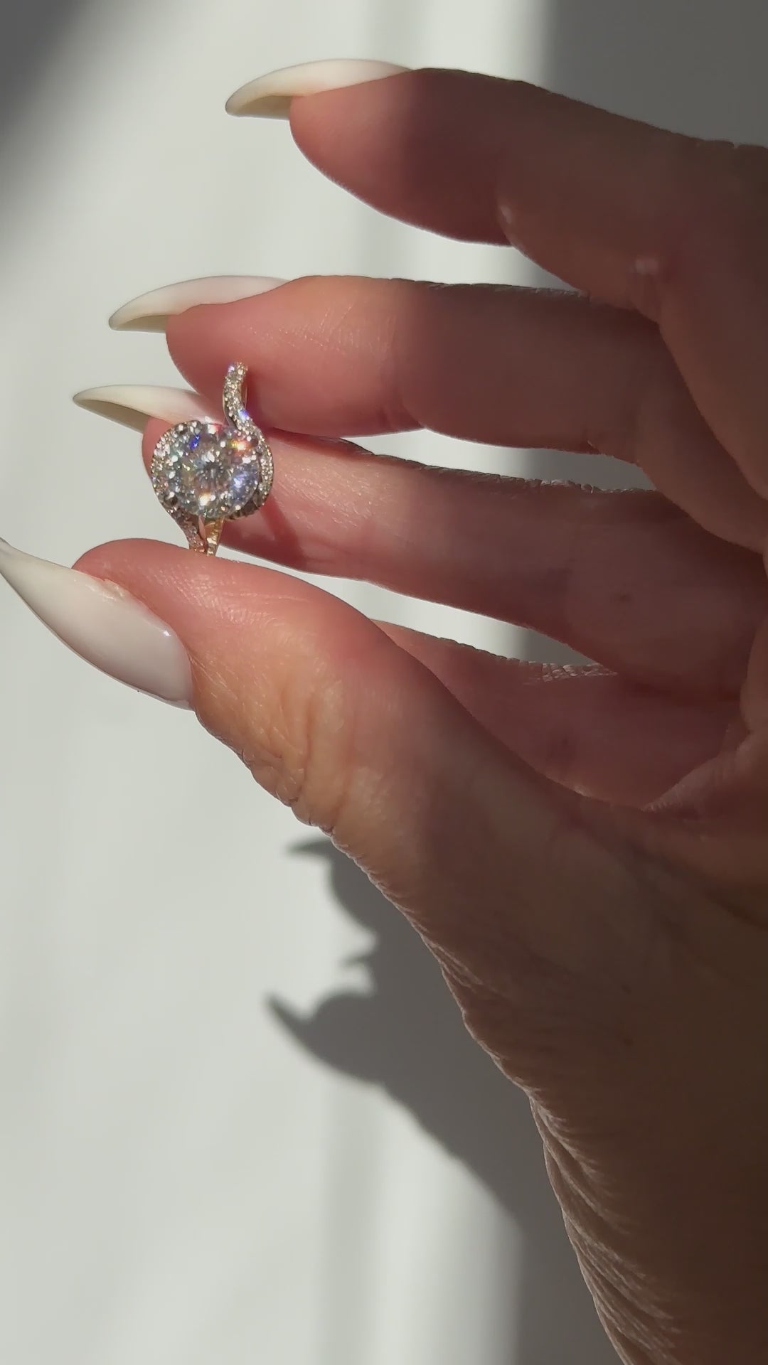 יד של אישה שמחזיקה טבעת אירוסין מואסנייט ויהלומי צד בזהב צהוב