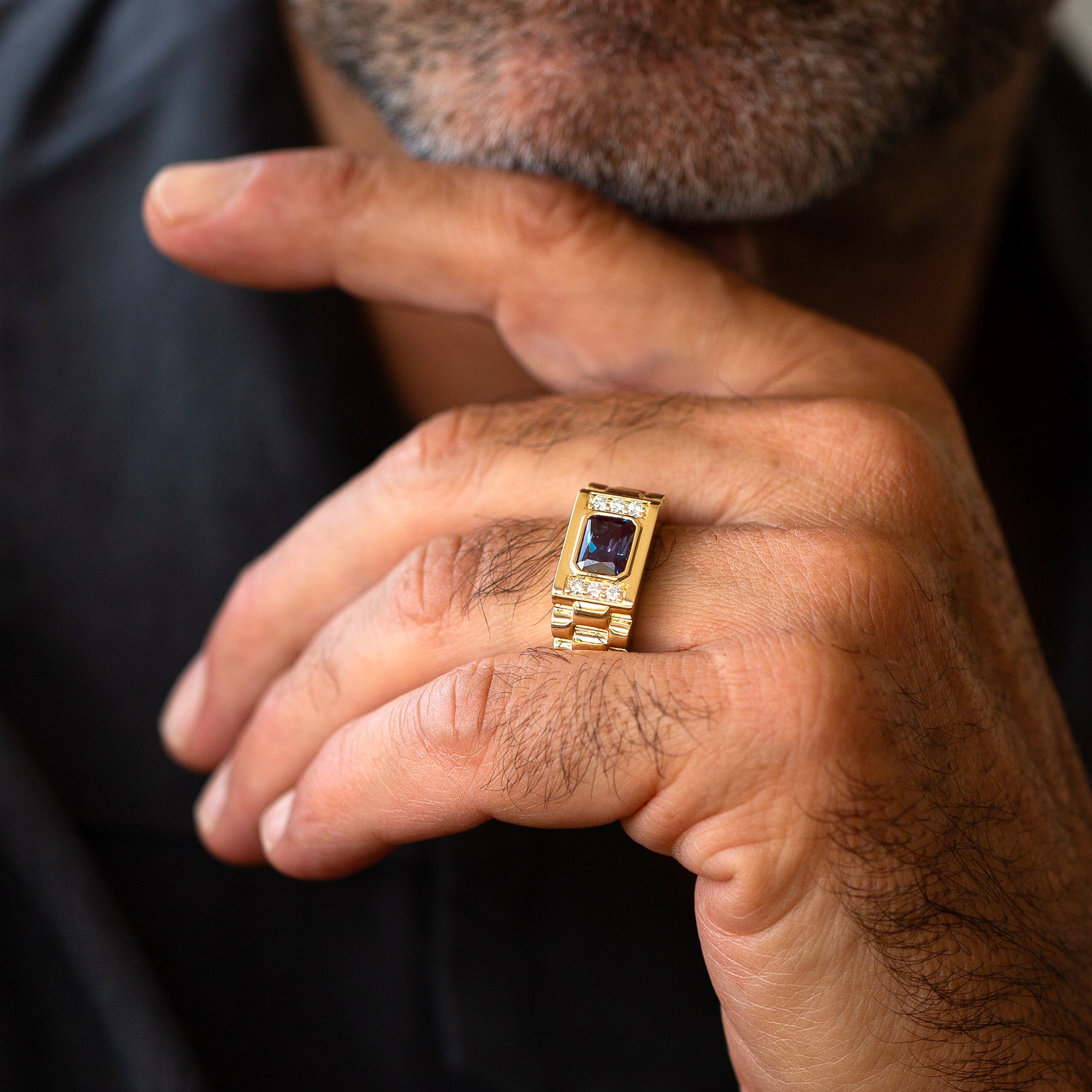 תקריב של יד של גבר שעונד טבעת אירוסין לגבר משובצת אלכסנדריט ויהלומי מעבדה