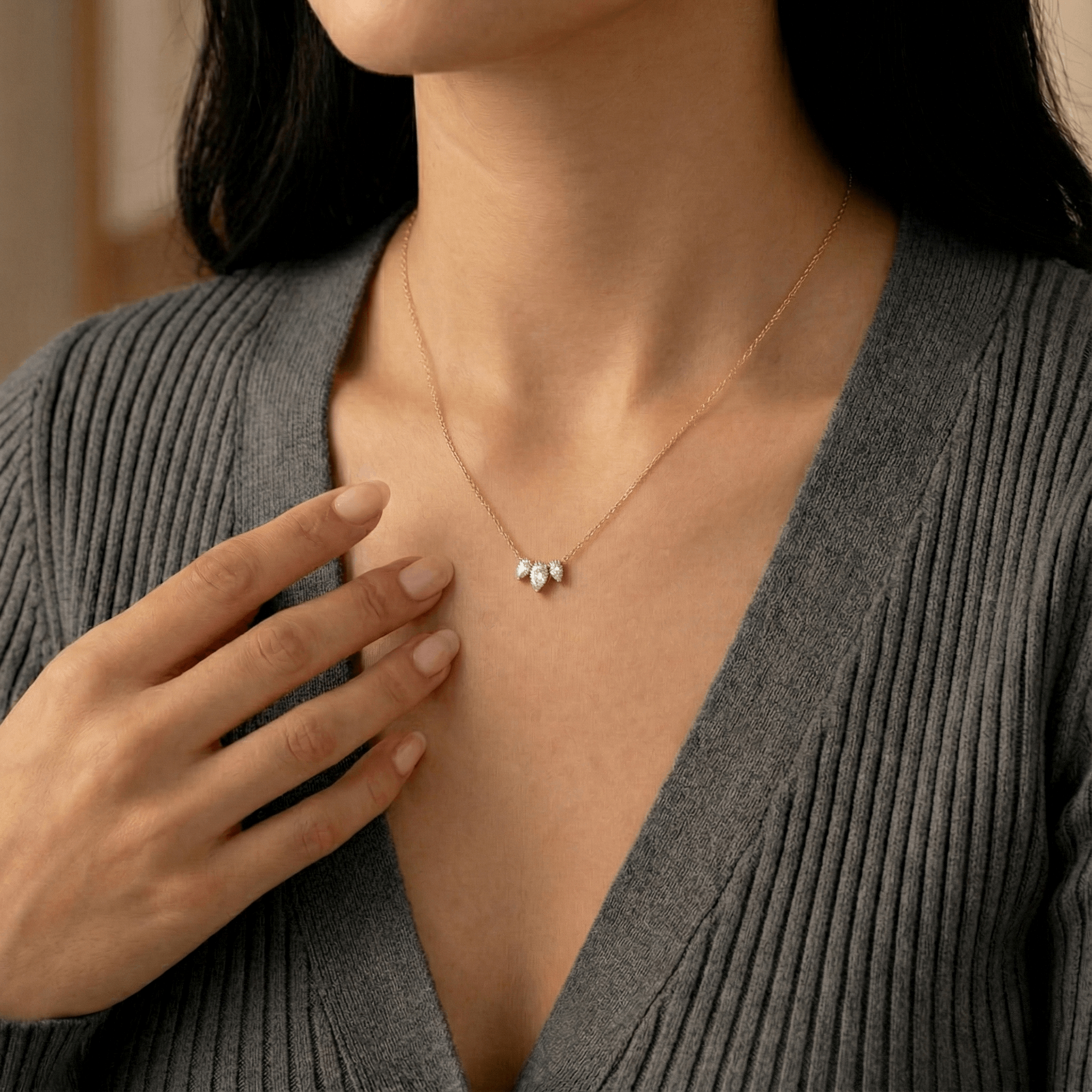 תקריב של אישה שעונדת שרשרת יהלומי מעבדה בחיתוך טיפה וחולצה אפורה