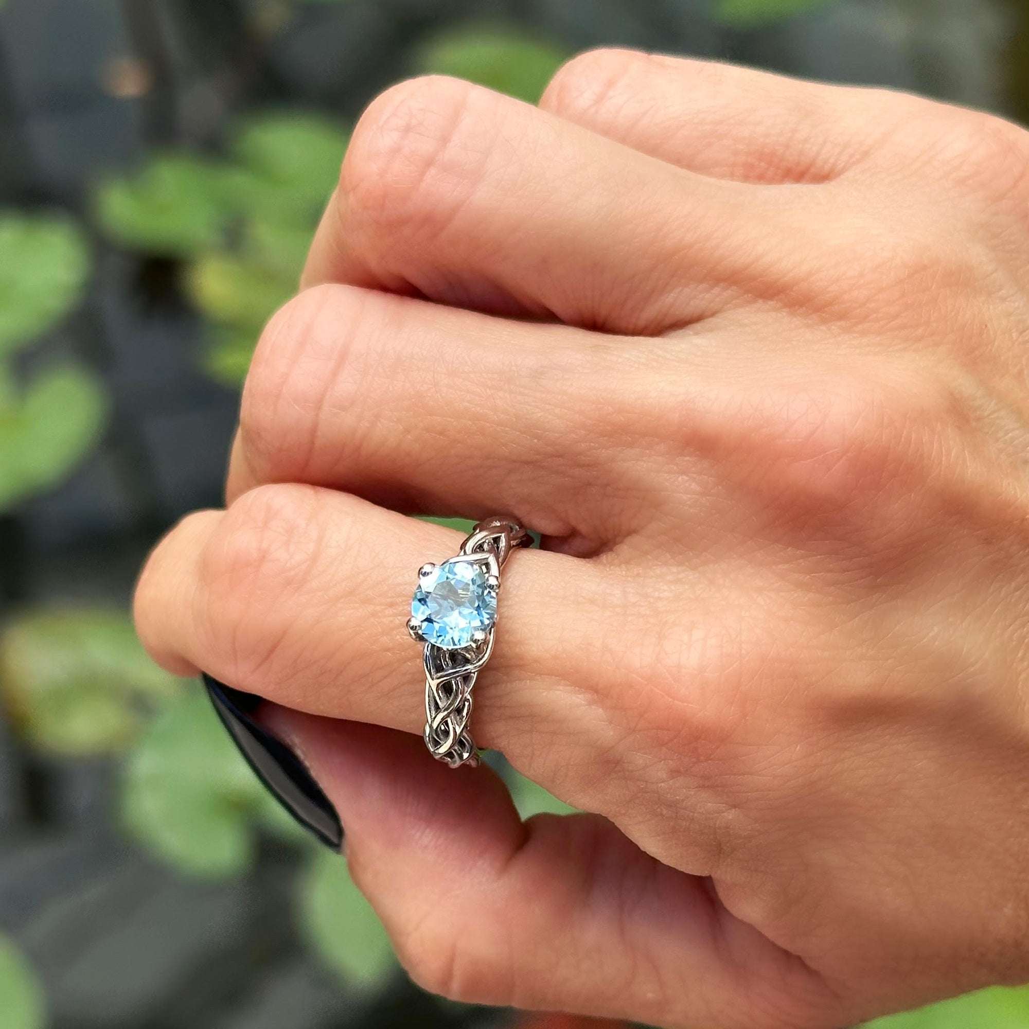 תקריב של יד של אישה שעונדת טבעת אקווה מרין כחולה